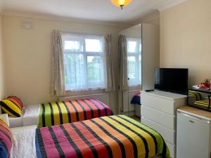 Habitación pequeña con 2 camas y TV. en Gladstone Lodge Guest House, en Londres