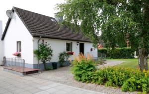 una casa blanca con un árbol y algunas flores en Ferienhaus Schlei, en Rabenkirchen-Faulück