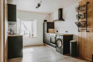 a kitchen with a stove and a washing machine at Wooden Soul : duplex 2 chambres avec jardin commun in Houffalize