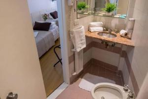 bagno con servizi igienici, lavandino e letto di Hotel Dion a Mar del Plata Altre 25 foto