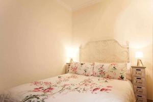 een slaapkamer met een wit bed met bloemen erop bij Dos dormitorios al lado del metro centrico moderno in Madrid