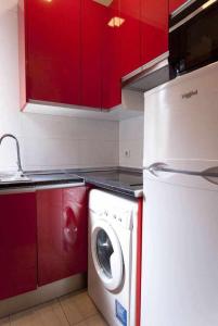 a kitchen with red cabinets and a washing machine at Dos dormitorios al lado del metro centrico moderno in Madrid
