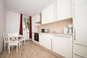 Rabenkirchen-FaulückにあるSchleiblick App 12の白いキャビネット、テーブルと椅子付きのキッチンが備わります。