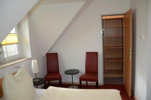 1 dormitorio con 2 sillas rojas y 1 cama en Am Deich 15, en Zingst