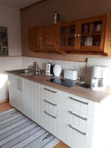 a kitchen with white cabinets and a sink at Lodge 31 in Neue Tiefe Fehmarn