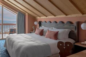 a bedroom with a large bed and a balcony at Hotel Le Coucou Méribel in Méribel