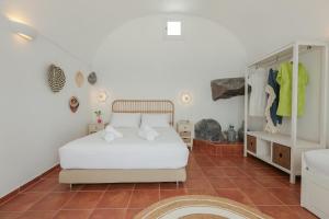 sypialnia z białym łóżkiem i podłogą wyłożoną kafelkami w obiekcie Petinos traditional house w mieście Thirasia
