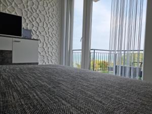 sypialnia z łóżkiem, telewizorem i balkonem w obiekcie Best Panoráma Apartman w Siófoku