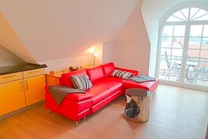 um sofá vermelho numa sala de estar com uma janela em Strandresidenz Deichgraf 8 em Zingst