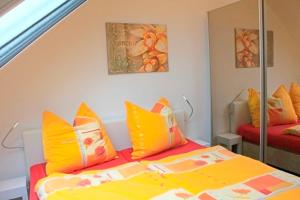 um quarto com uma cama com almofadas amarelas e laranja em Strandresidenz Deichgraf 8 em Zingst