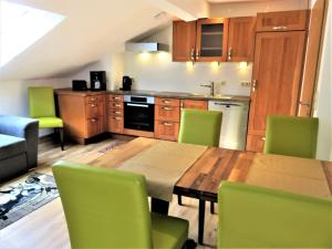 cocina con mesa de madera y sillas verdes en Ferienhaus Weiß, Sandra Weiß en Füssen