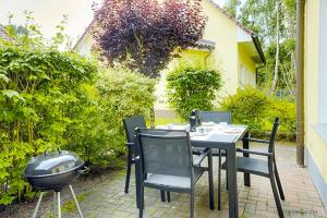 a patio with a table and chairs and a grill at Am Deich 44 in Zingst