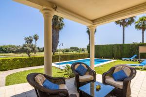 eine Terrasse mit Stühlen, einem Tisch und einem Pool in der Unterkunft Villa Lujo Olivanova Golf MET in Oliva