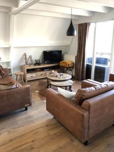 Una sala de estar con dos sofás y un televisor. en De Berghut Durbuy - Chalet nr 104, en Durbuy