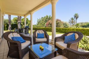 une terrasse couverte avec des chaises en osier et une table. dans l'établissement Villa Lujo Olivanova Golf MET, à Oliva