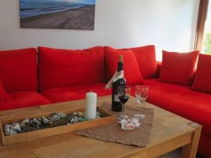 a red couch with a bottle of wine and two glasses at Haus Cathleen Wohnung 1 in Dahme