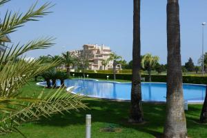 a swimming pool in a resort with palm trees at Brisa de Mar en Oliva Nova, junto a MET y golf in Oliva