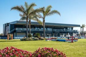 a building with palm trees in front of a park at Brisa de Mar en Oliva Nova, junto a MET y golf in Oliva
