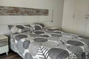 a bedroom with a bed with a black and white comforter at Brisa de Mar en Oliva Nova, junto a MET y golf in Oliva +20 photos