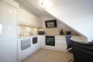 une cuisine avec des placards blancs et un comptoir dans l'établissement Apartment am Kunsthaus Nordhausen, à Nordhausen