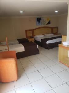 a hotel room with two beds and a couch at Gran Roza Hotel in Patos de Minas