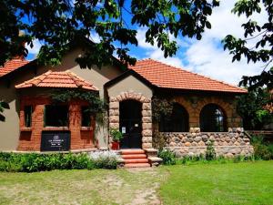 Casa con un edificio de piedra con techo rojo en Posada La Diamela en La Cumbre