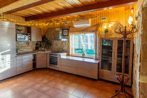 a kitchen with wooden cabinets and a large window at Sodyba "Baltalaukis" in Didžiosios Kabiškės