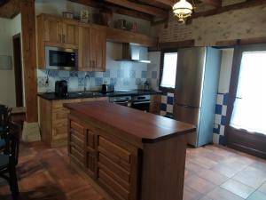 a kitchen with wooden cabinets and a refrigerator at Casa Rural Las Cotarras in Sanchonuño