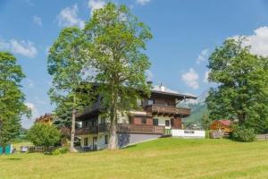 une grande maison avec un arbre sur une colline dans l'établissement Soldanella 3 by Alpenidyll Apartments, à Ramsau am Dachstein