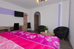 a bedroom with a pink bed with two chairs and a desk at Das Arni´s in Mehlmeisel