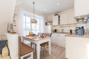 a white kitchen with a table and chairs in it at Lütten Kate 03 in Zingst