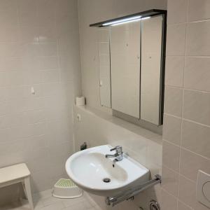 a white bathroom with a sink and a mirror at Apartment 113 in Wilhelmshaven