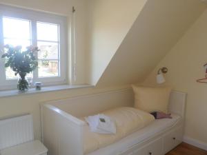 een wit bed in een kamer met een raam bij Lillebroo in Boldixum