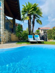 - une piscine avec 2 chaises et un palmier dans l'établissement Franciacorta Suite, à Corte Franca