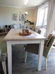 - une table à manger blanche avec un vase dans l'établissement LANDHAUS AM SUND im EG, à Lütjenbrode