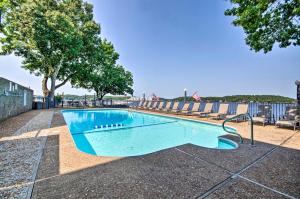 a blue swimming pool with chairs and trees at Waterfront Ozark Gem with Pool Access and Lake Views! in Lake Ozark