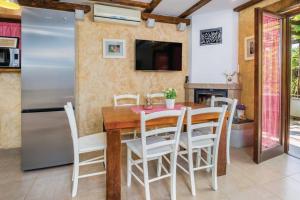 Il comprend une cuisine et une salle à manger avec une table en bois et des chaises blanches. dans l'établissement Holiday House - Old Olive, à Porozina