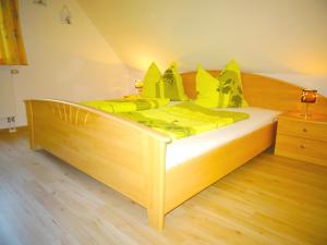 ein Holzbett mit gelber Bettwäsche und gelben Kissen in der Unterkunft Birkenstraße 6j in Zingst