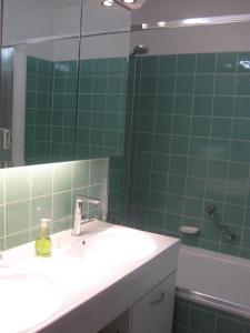 Baño de azulejos verdes con lavabo y espejo en Ferienwohnung Plaggemars Verm nur Sonntag auf Samstag en Seehausen am Staffelsee