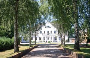 una casa blanca con árboles delante de ella en Ferienhof Rauert Haus 3, en Todendorf auf Fehmarn