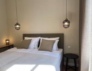 a bedroom with a white bed with two pendant lights at Apartments 19 in Zagreb