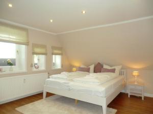 ein weißes Bett in einem Zimmer mit Fenster in der Unterkunft Seemöwe 5 Herrenhof in Wrixum