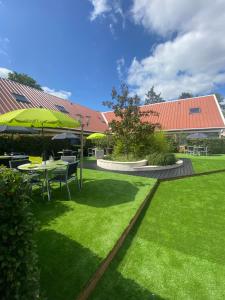 a green yard with a table and an umbrella at Contact Hotel Be Guest Limoges Sud in Limoges