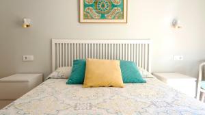 a bedroom with a bed with blue and yellow pillows at Sevilla Alameda PG Apartamentos in Seville