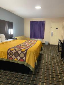 a hotel room with a bed with a yellow blanket at New Hampshire Inn West Memphis in West Memphis