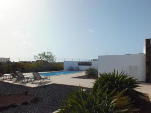 a backyard with chairs and a swimming pool at Heated & Shared Pool VILLA MATRIANA 36B, North Shore Villas in La Oliva