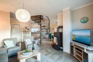 a living room with a television and a spiral staircase at Wellness - Ferienhaus Ostküste in Klausdorf