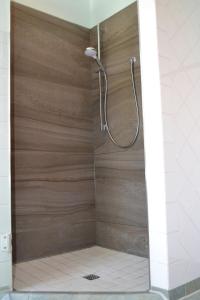 een douche met een houten wand in de badkamer bij Ferienwohnung Bülte in Papenburg