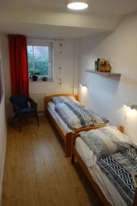 two beds in a room with a chair and a window at Haus Mehler in Heiligenhafen