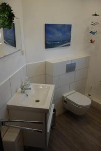 a white bathroom with a toilet and a sink at Haus Mehler in Heiligenhafen